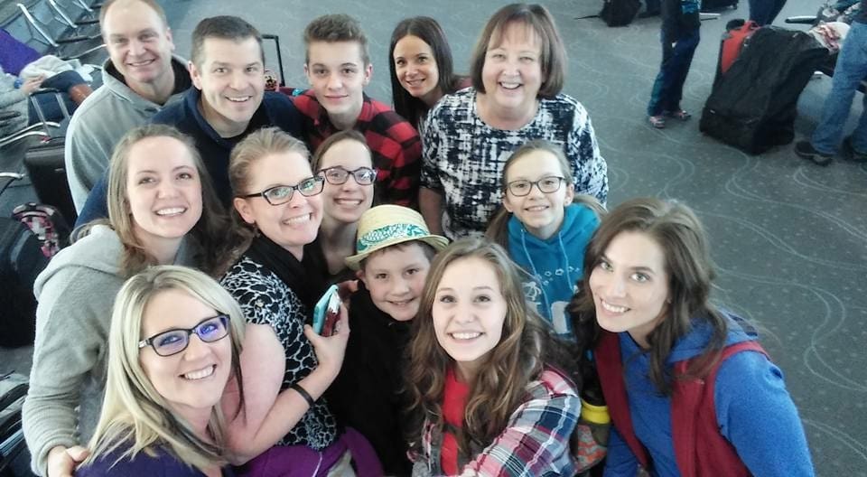 Group selfie of smiling people at airport.