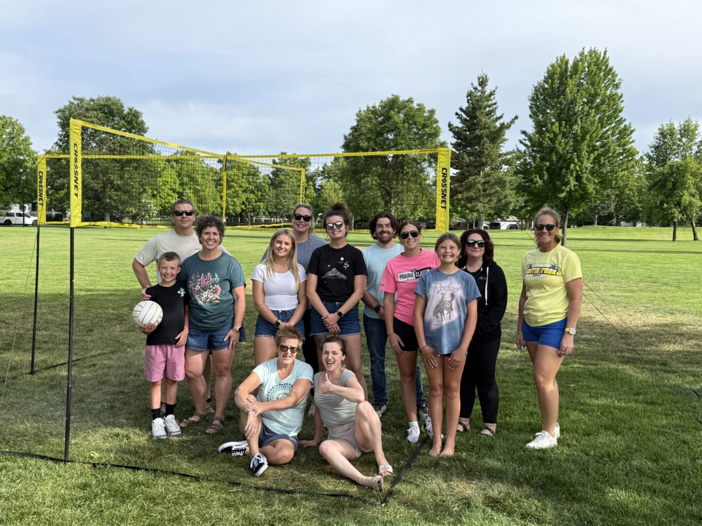 Group posing by volleyball net in park.
