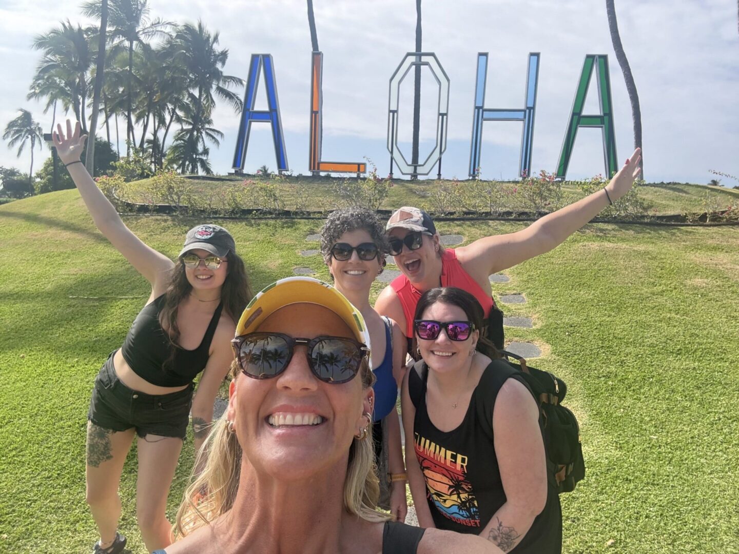 Group selfie in front of Aloha sign