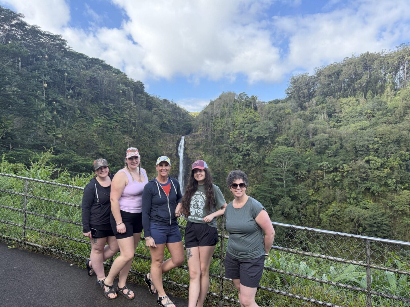 Friends posing near lush waterfall