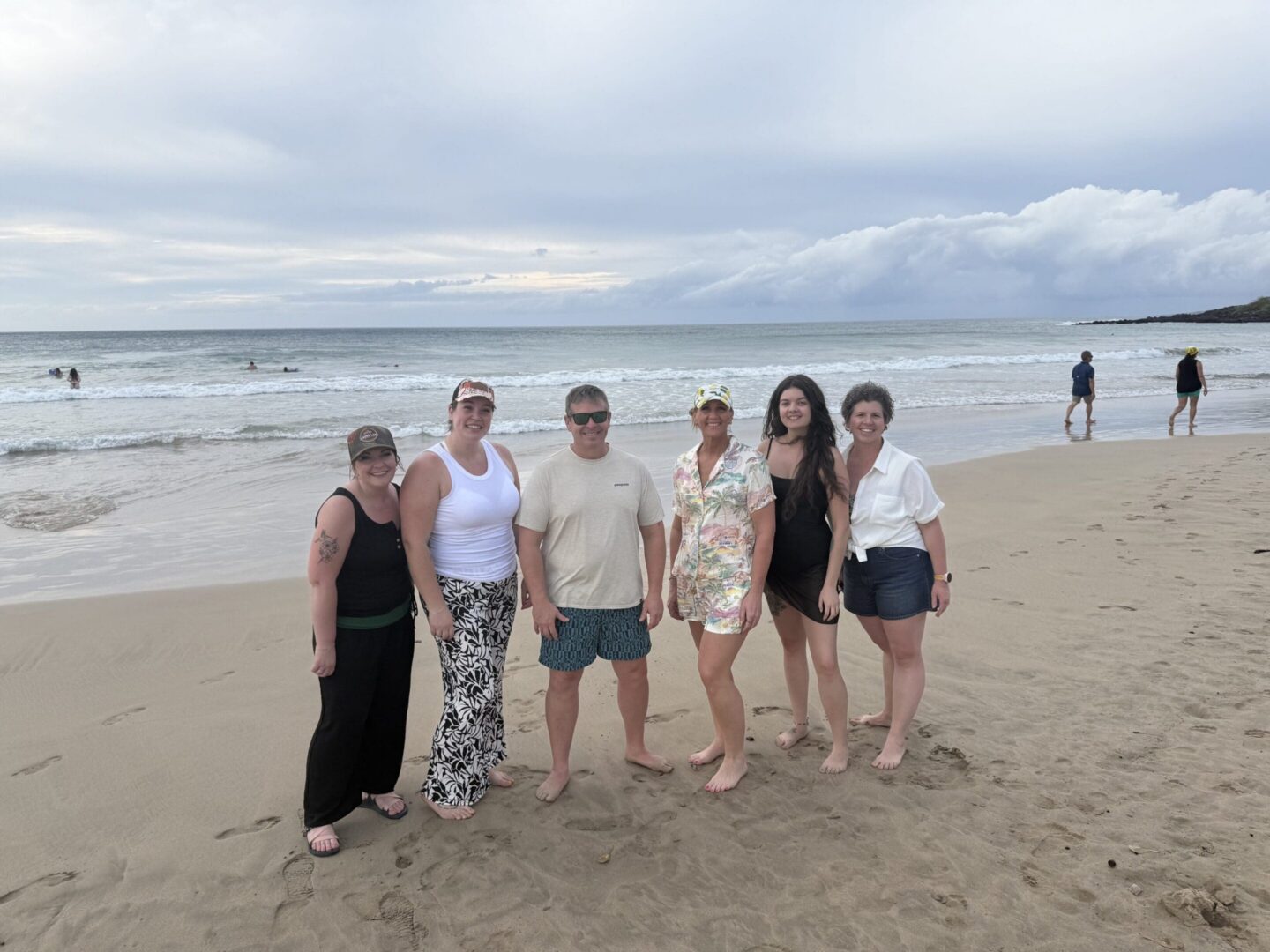 Friends standing together on sandy shore.