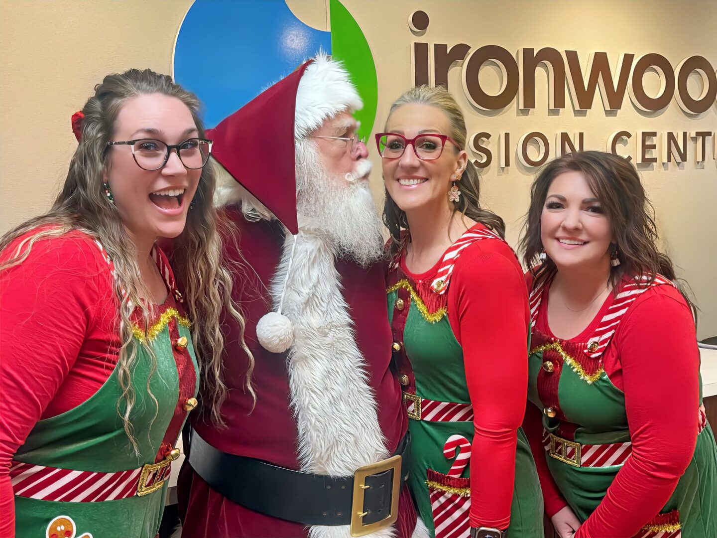 Smiling elves and Santa in holiday attire
