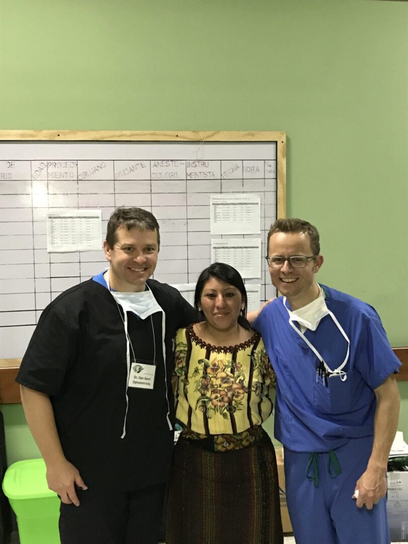 Three people smiling in front of board
