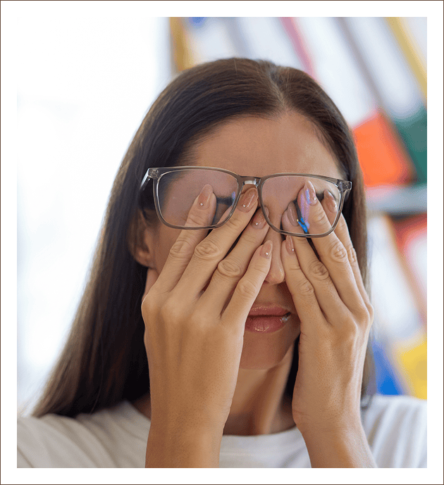 Individual with glasses rubbing eyes