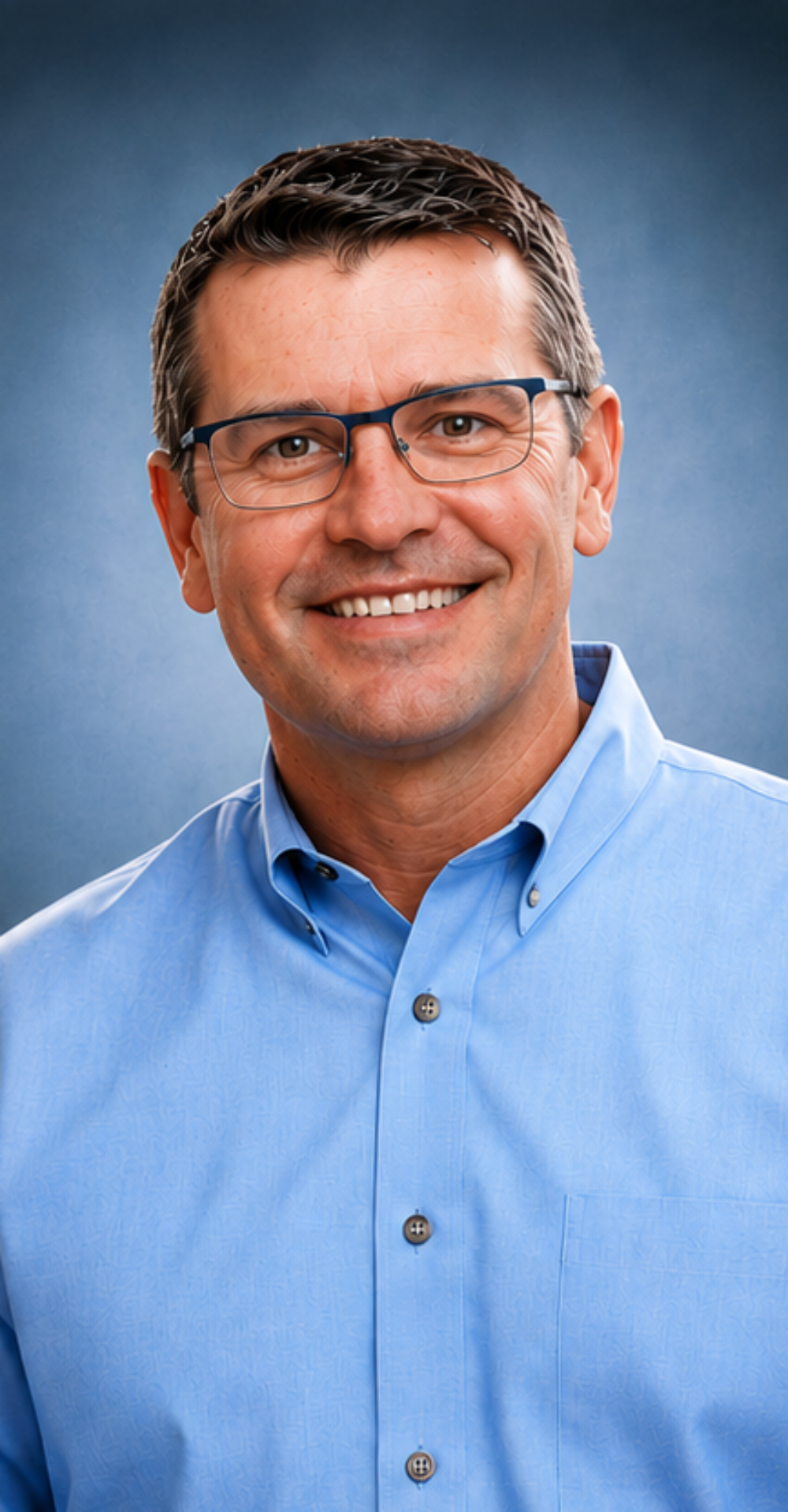 Smiling man wearing glasses and blue shirt.